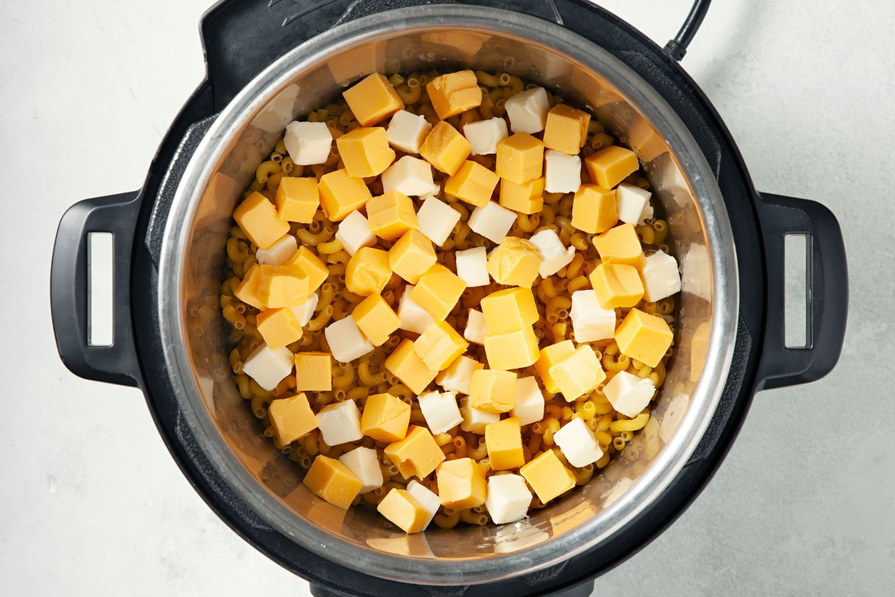 Elbow macaroni, chicken broth, butter and Velveeta In a 6-quart electric pressure cooker.