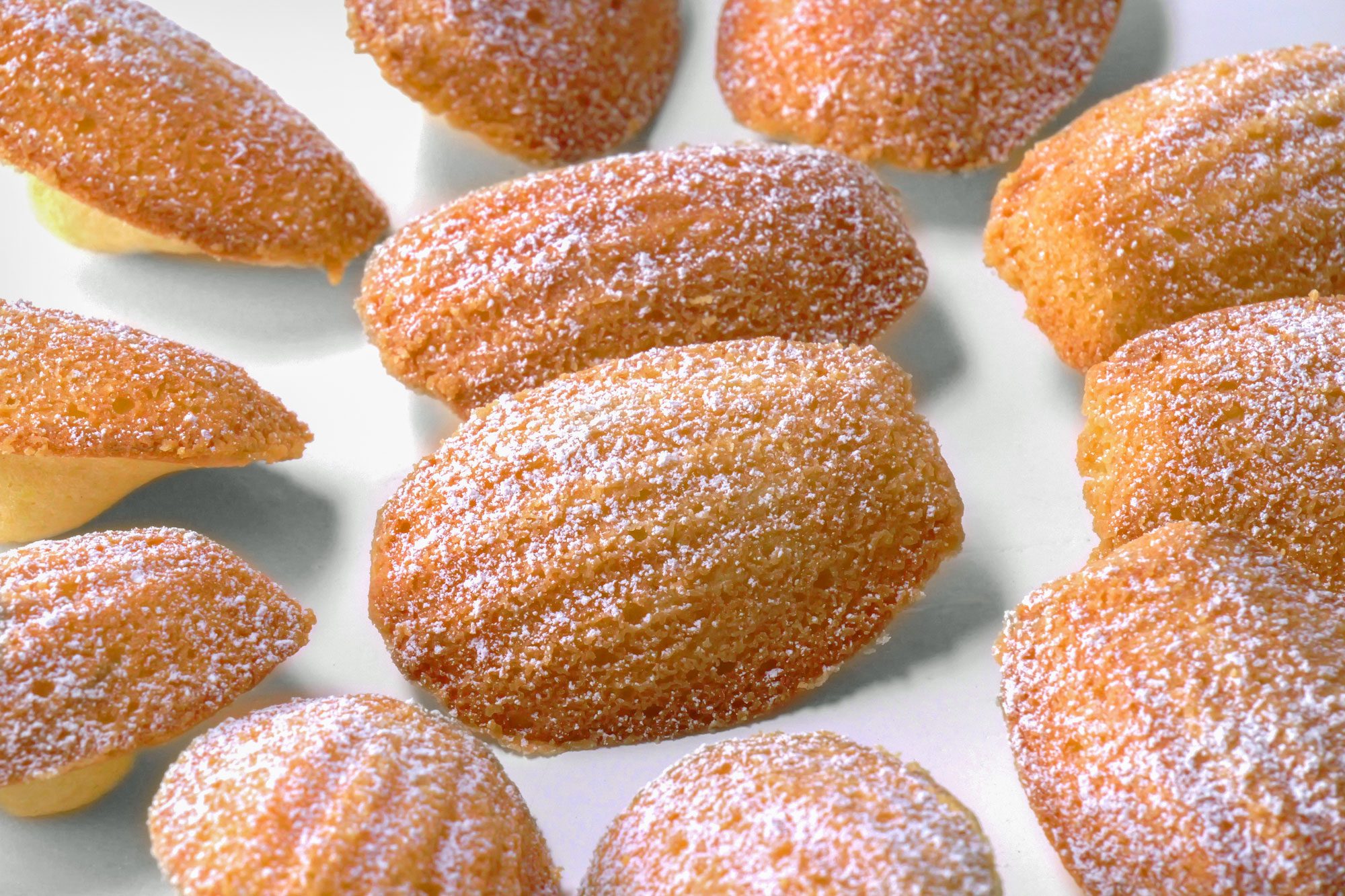 close shot of madaleine cookies dusted with confectioner's sugar