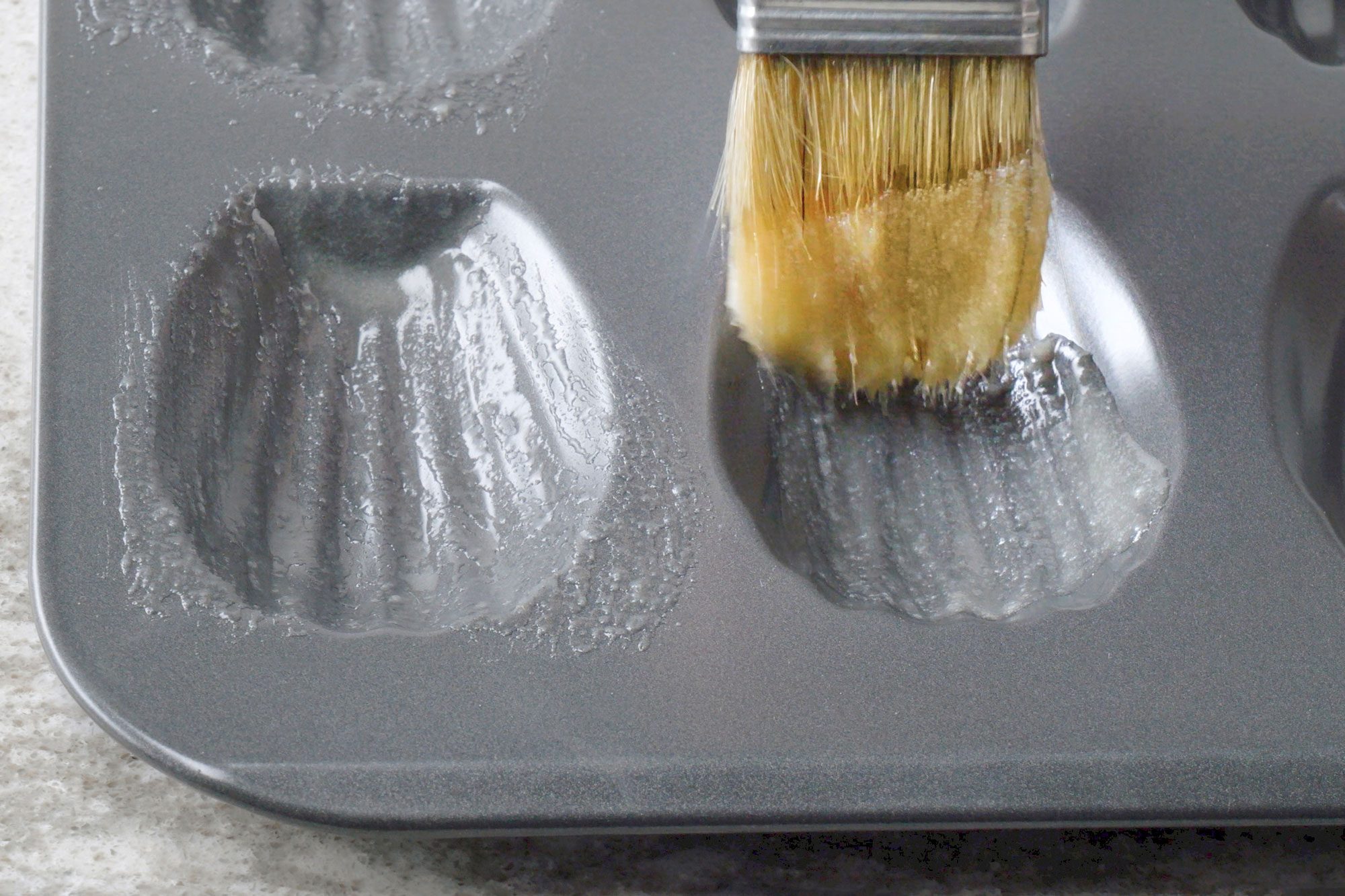 Use a pastry brush to coat wells of a madeleine pan.