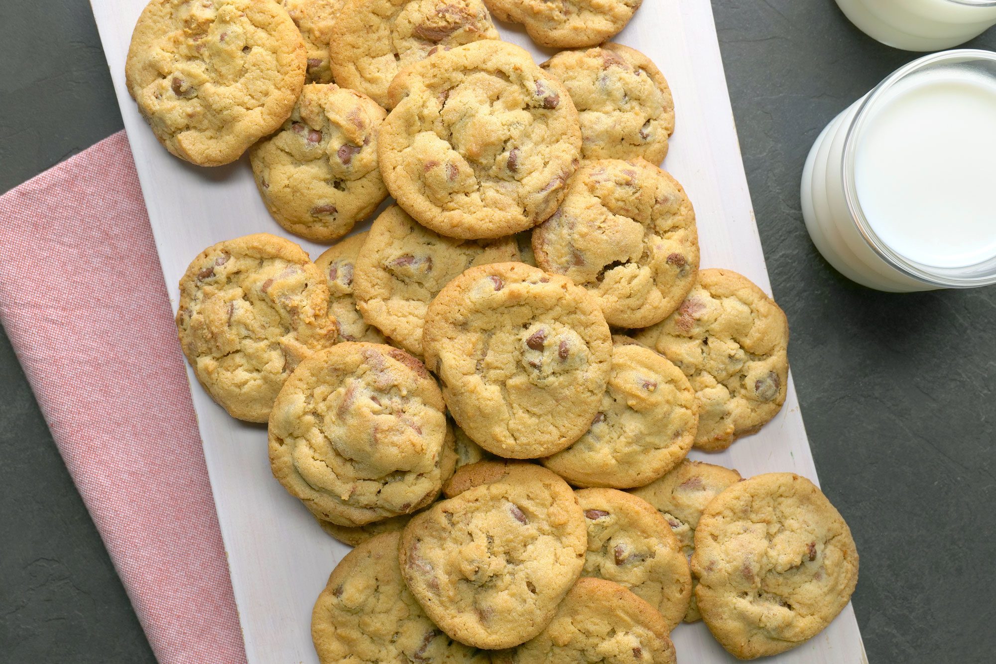 Peanut Butter Cup Cookies placed on white board over kitchen towel with two glasses of milk