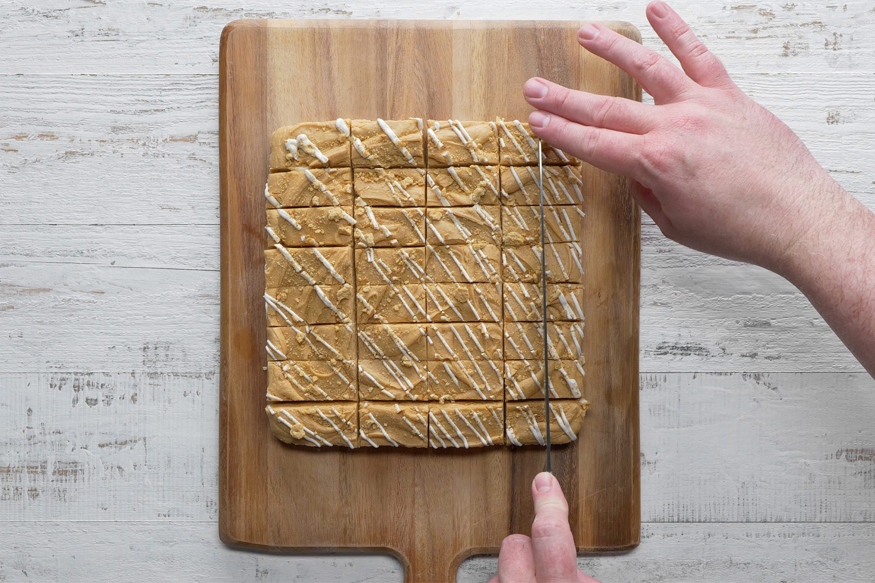 Overhead shot of cut into squares; chopping board; knife; white wooden background;