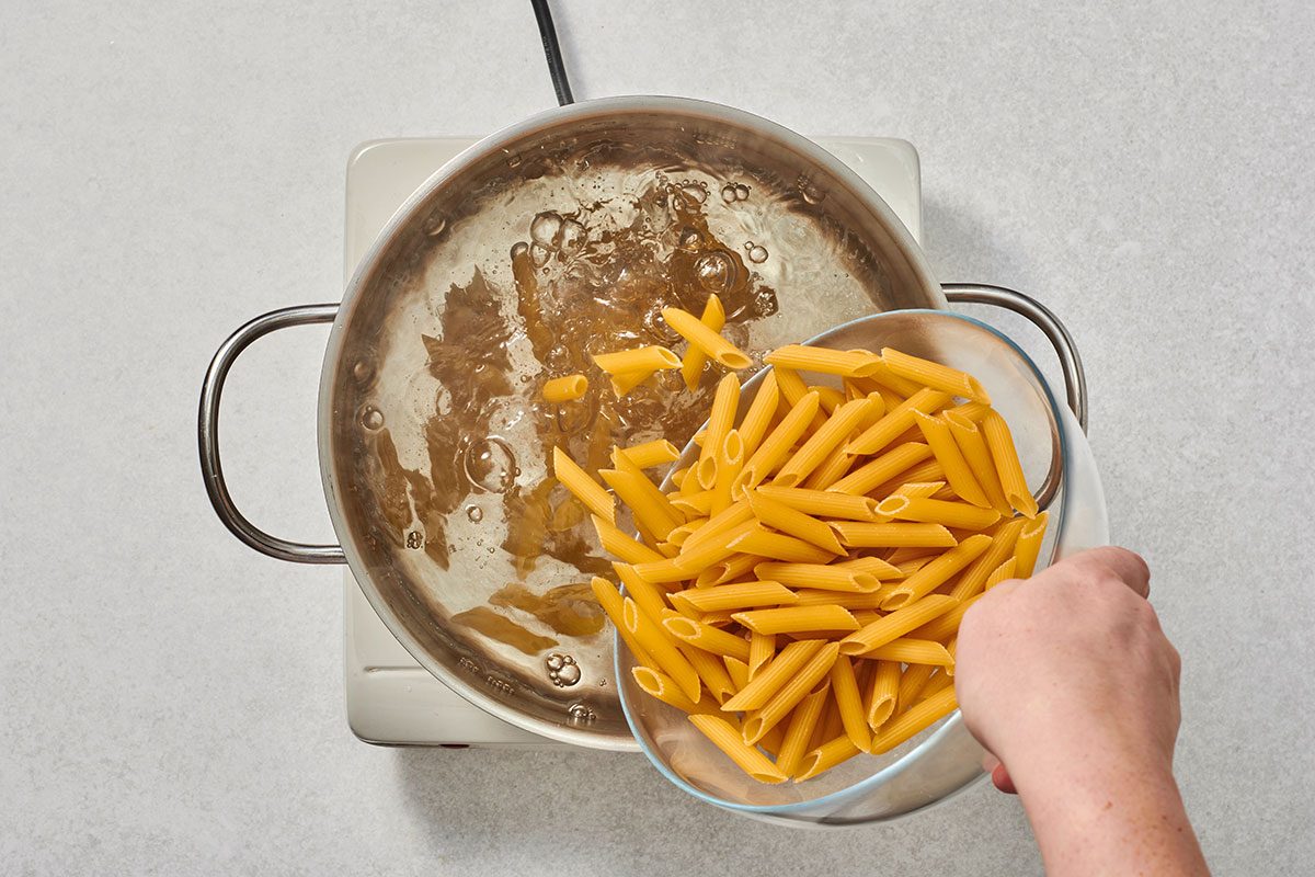 Adding pasta to boiling salted water in a pot