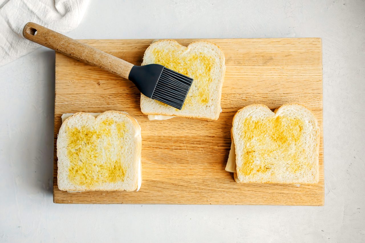 Overhead shot for Taste of Home Pesto Grilled Cheese, olive oil being spread on bread.