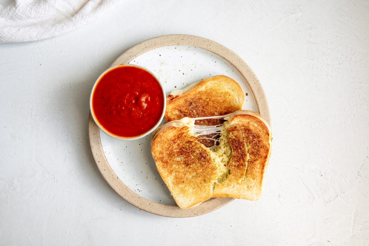 Overhead beauty shot for Taste of Home Pesto Grilled Cheese, sandwich on plate with warmed pizza sauce. 