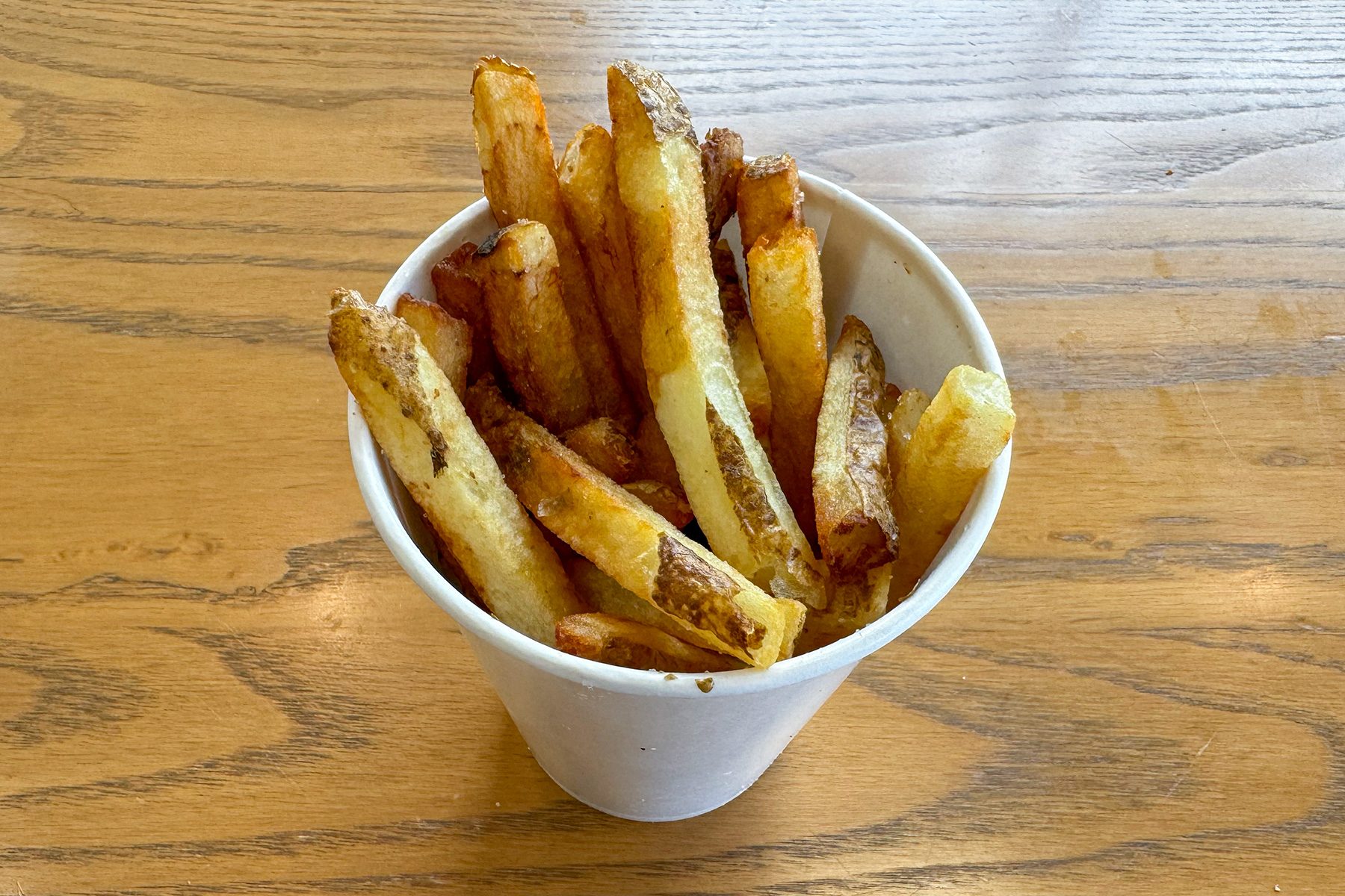 Extra Crispy Fries in a cup on wooden base