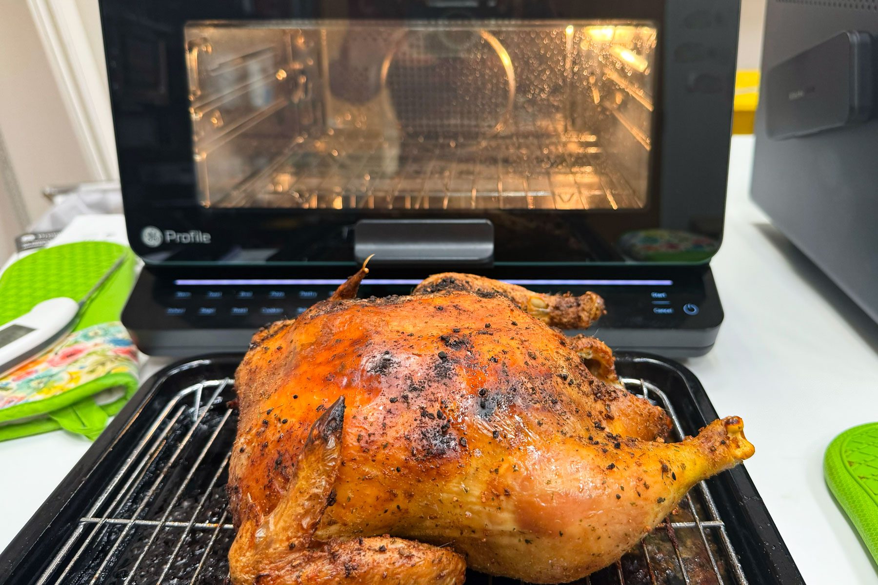 GE Air Fryer toaster oven in the background with a chicken in the foreground