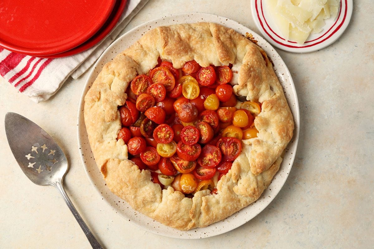 Close up of Taste of Home's Tomato Galette served on a red plate with a beige marble countertop.