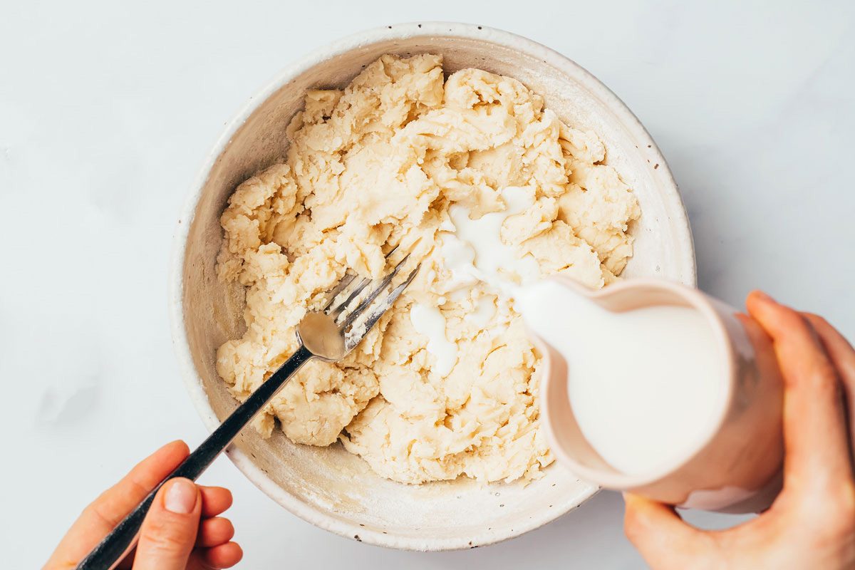 Adding milk to the dough mixture into a large bowl for making the crust for the Cinnamon Apple Pie recipe by Taste of Home