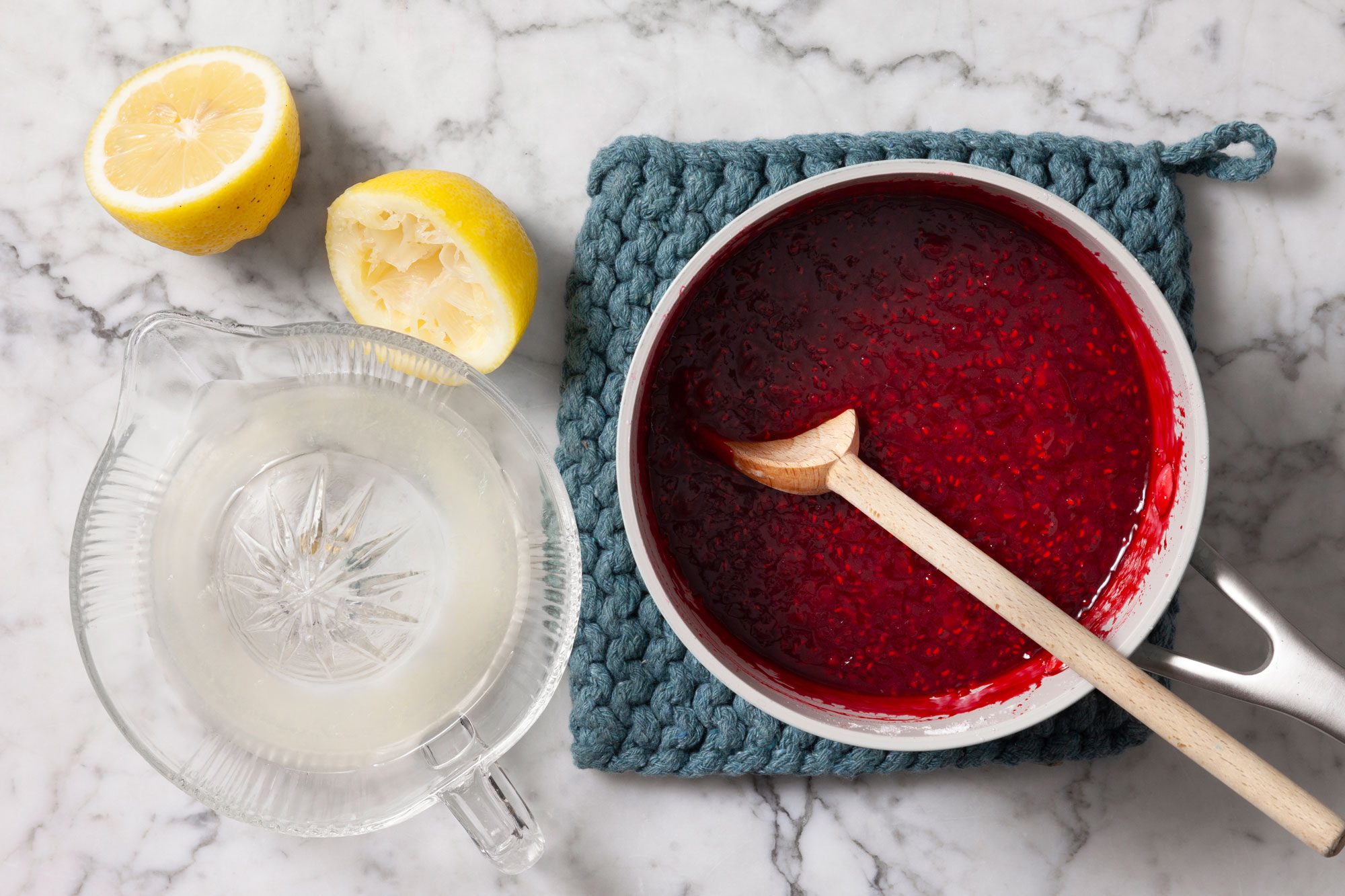 Saucepan filled with a vibrant red mixture, The mixture consists of cooked raspberries, sugar, and lemon juice